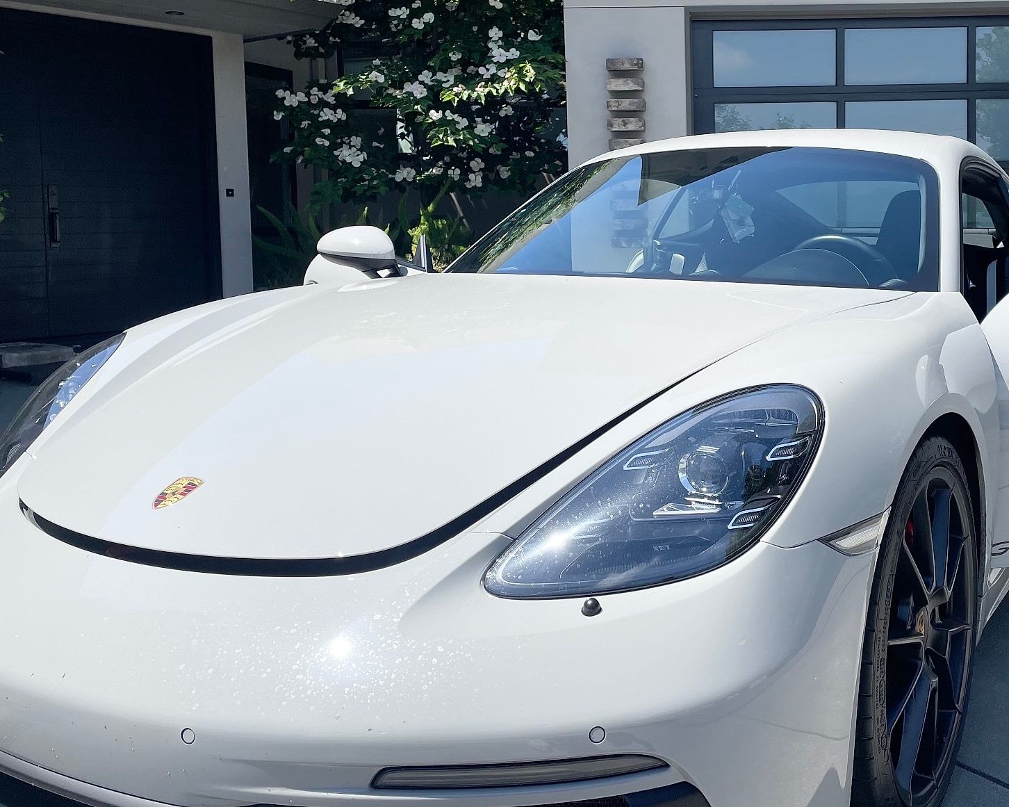 White Porsche Cayman GTS with a clear windshield, photographed on a mobile job